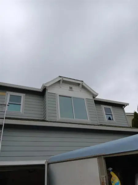 New windows set in a dormer and upper wall on a gray two-story
