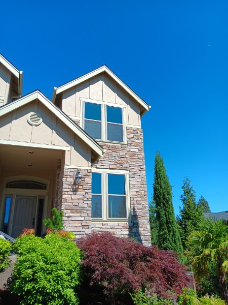 Two-story Washington house with stone veneer and cream vinyl windows after replacement
